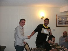 Joe presents the 'Best Driver' award to Karan who trys to speed out of the picture